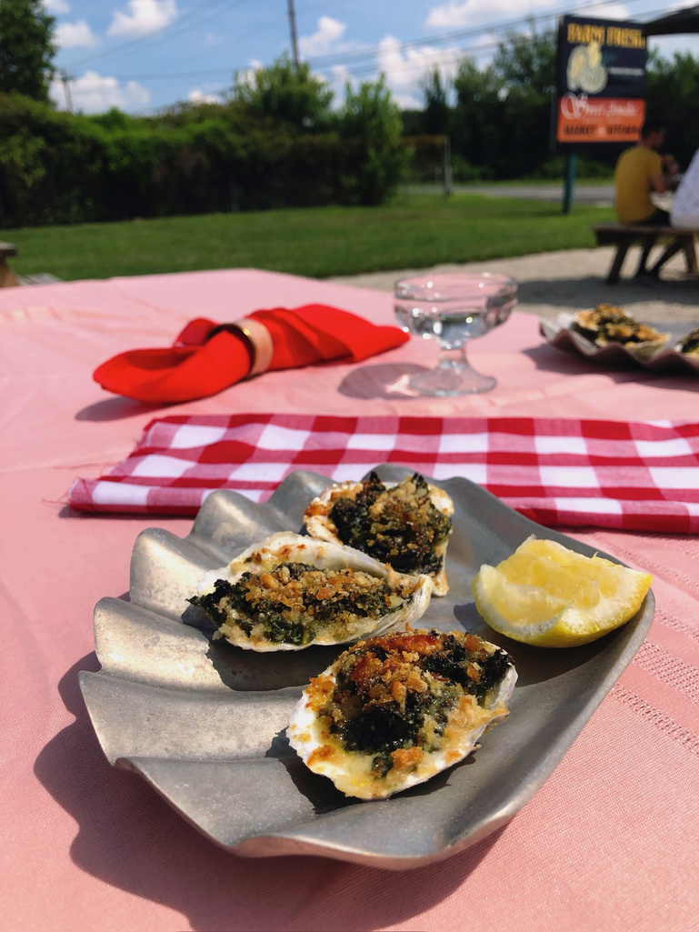 a couple of oysters and lemons on a plate on a pink clothed picnic table