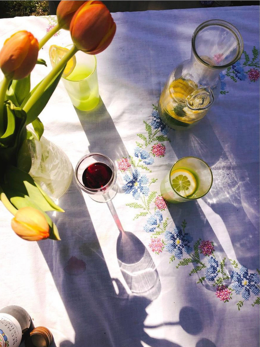 a vase of flowers and a glass of lemonade and a glass of wine on a table