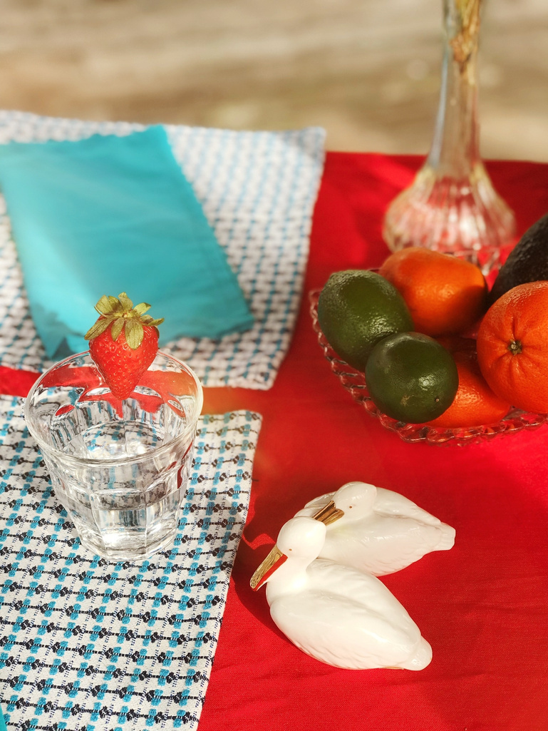 a table with fruit and a glass of water on it, decorated with a strawberry.