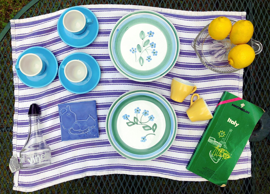 a picnic table with blue and white plates, cups and lemons