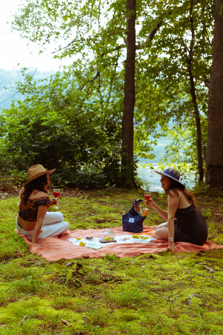 two people sitting on a picnic blanket in the woods