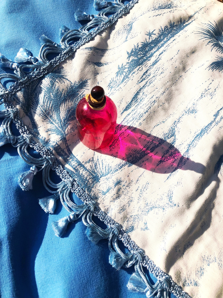 a pink bottle sitting on top of a blue tropical printed table runner