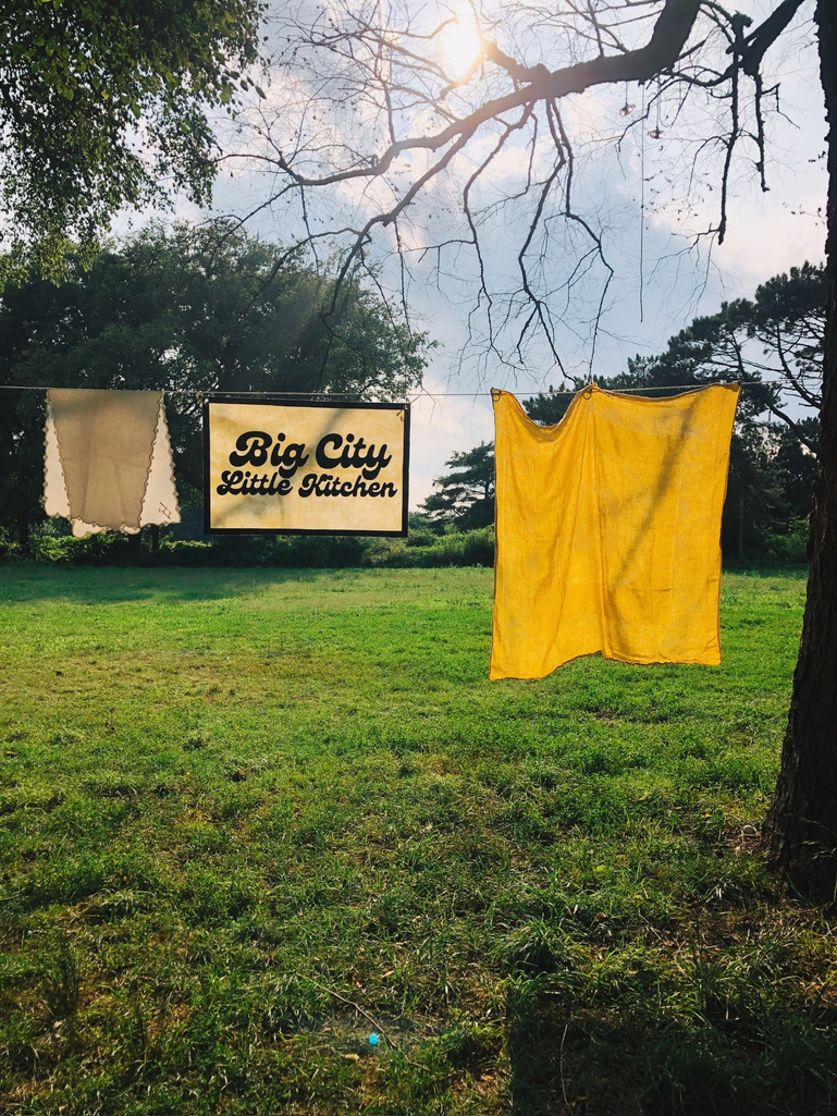 two yellow tablecloths hanging on a clothesline in a grassy field