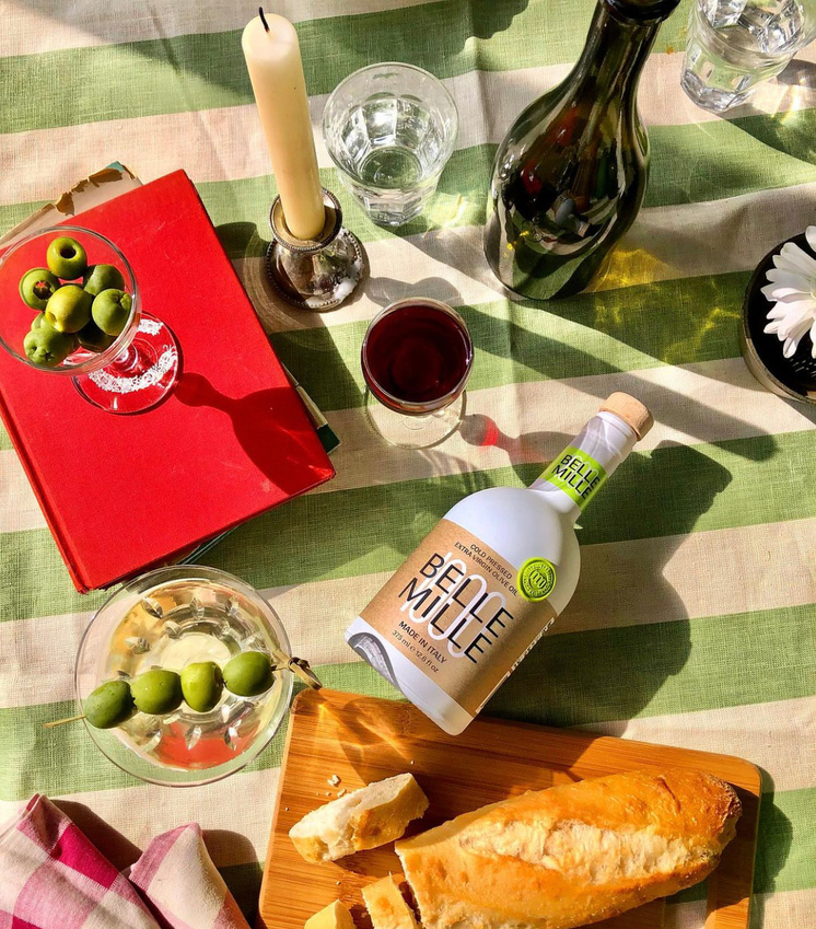 bottles of wine, bread and olives sit on a table