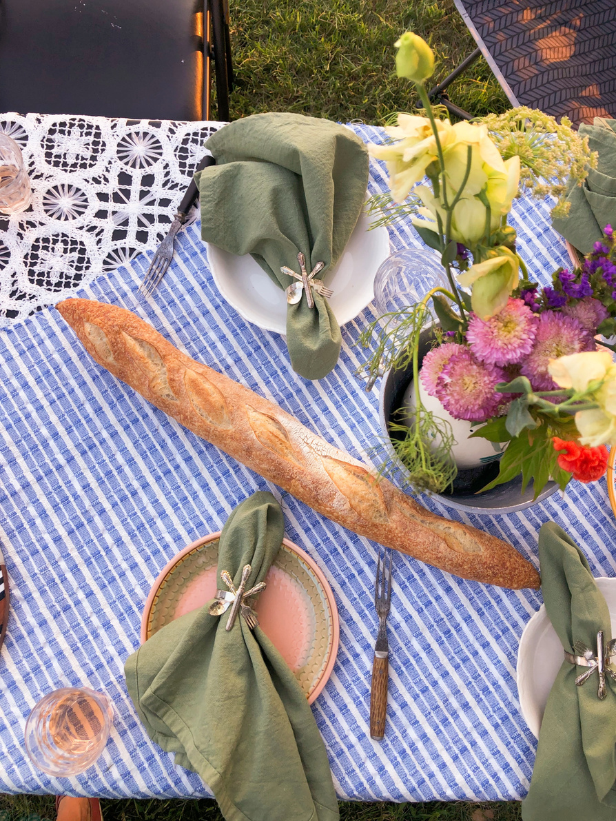 tablecloth is blue and white with bread and flowers and wine glasses.