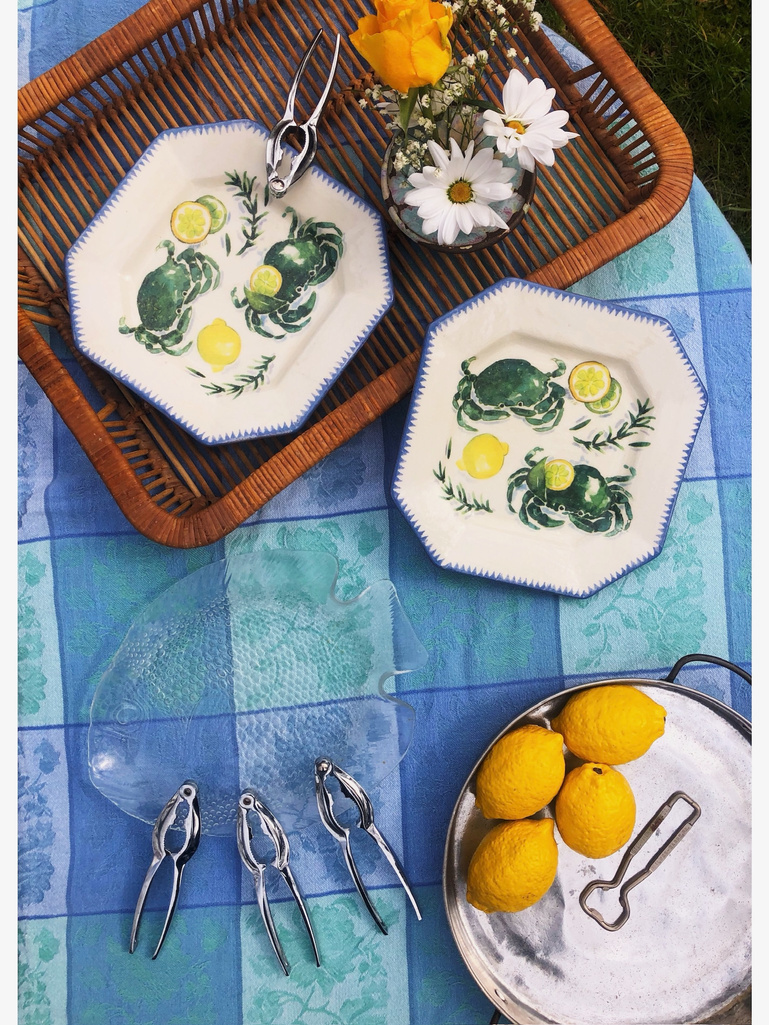 two plates with lemons and other items on a wicker tray on a blue and teal checkered tablecloth